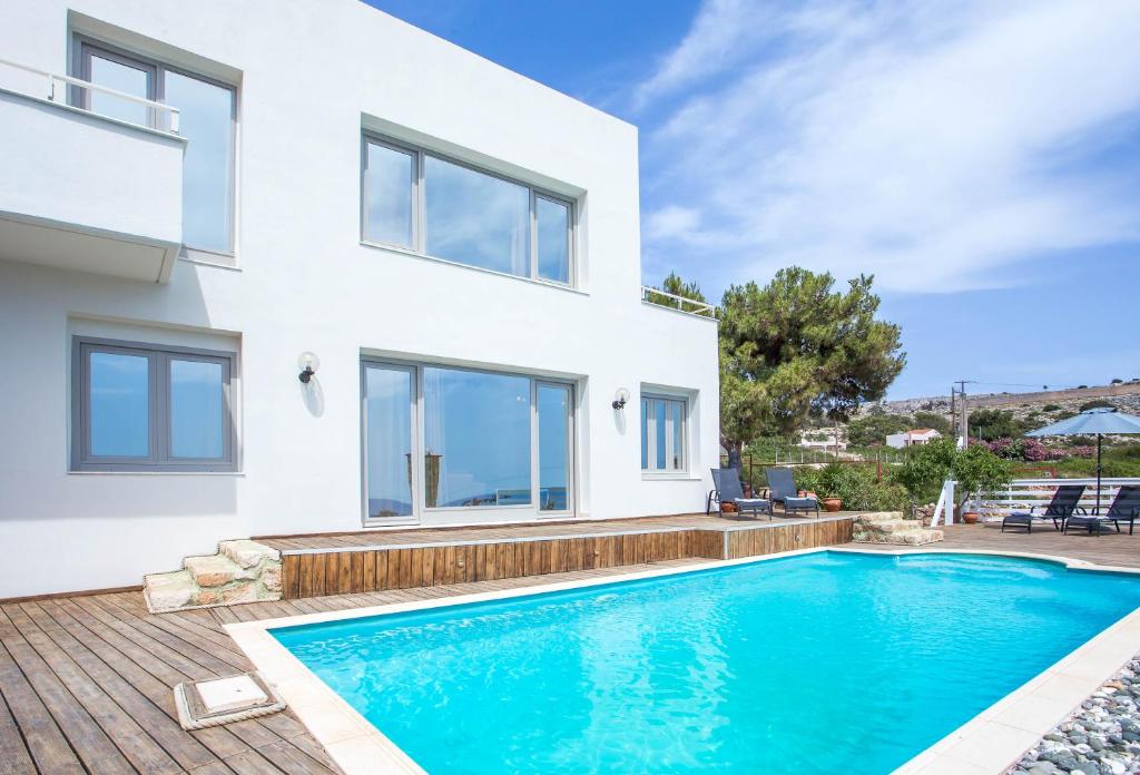 a villa with a swimming pool in front of a house at Spilia Bay Villas in Pefki