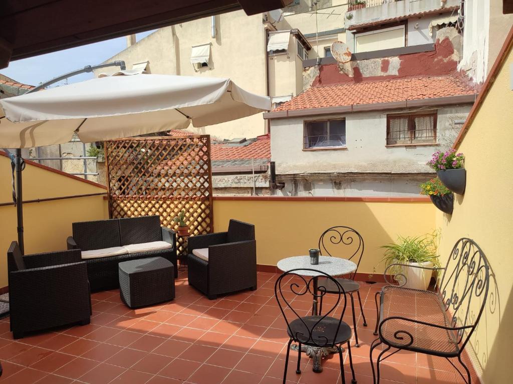 um pátio com uma mesa, cadeiras e um guarda-sol em Archubintu B&B your friendly place em Sassari