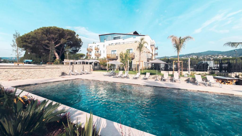 a swimming pool with chairs and a building at Ilot du Golf BW Premier Collection in Mandelieu-La Napoule