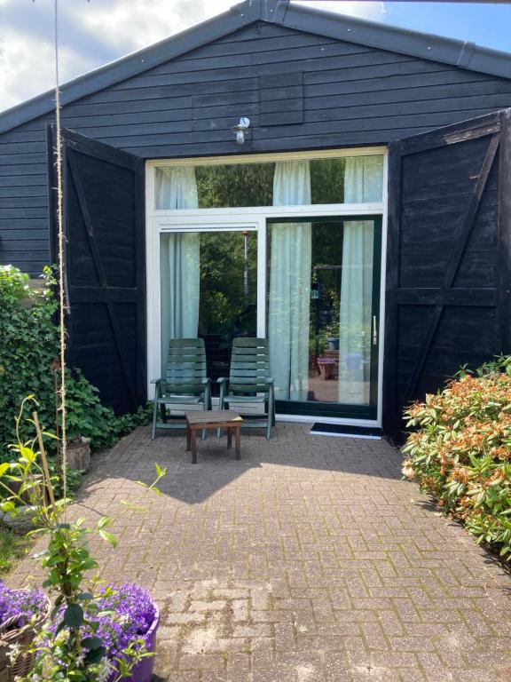 une maison noire avec deux chaises et une table dans l'établissement Assen-Groningen-Saunacabine, à Vries