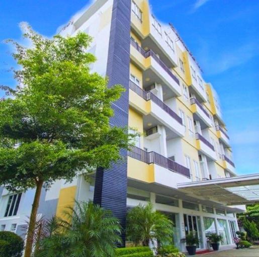 wysoki budynek z drzewem przed nim w obiekcie Bangka City Hotel w mieście Pangkal Pinang