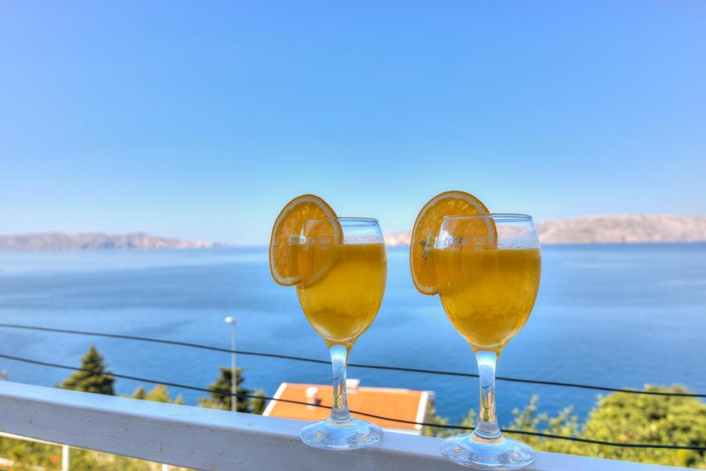 two glasses of wine sitting on a balcony overlooking the water at Ivan apartman in Senj