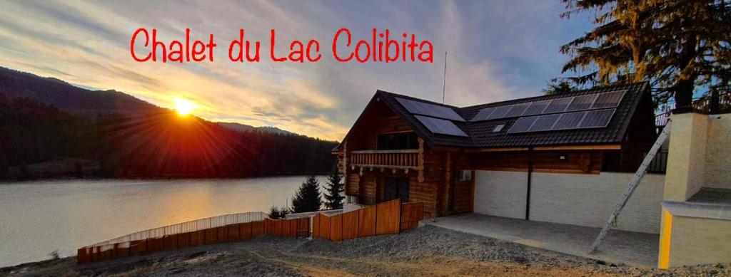 ein Haus mit einem Sonnendach auf einem See mit Sonnenuntergang in der Unterkunft Chalet du Lac in Colibiţa