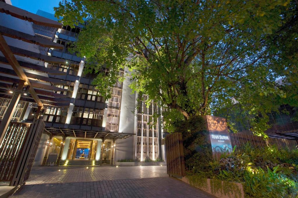 a building with a tree in front of it at Riva Surya Bangkok - SHA Extra Plus in Bangkok