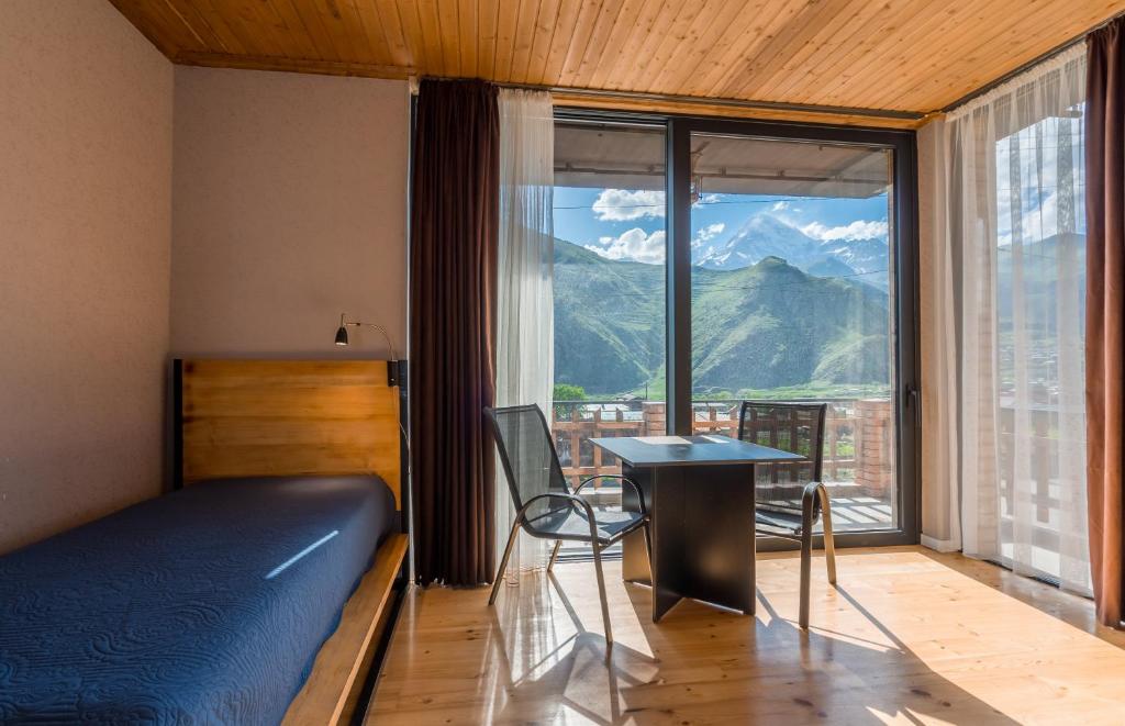 a bedroom with a bed and a table and a window at Vache Hotel in Kazbegi