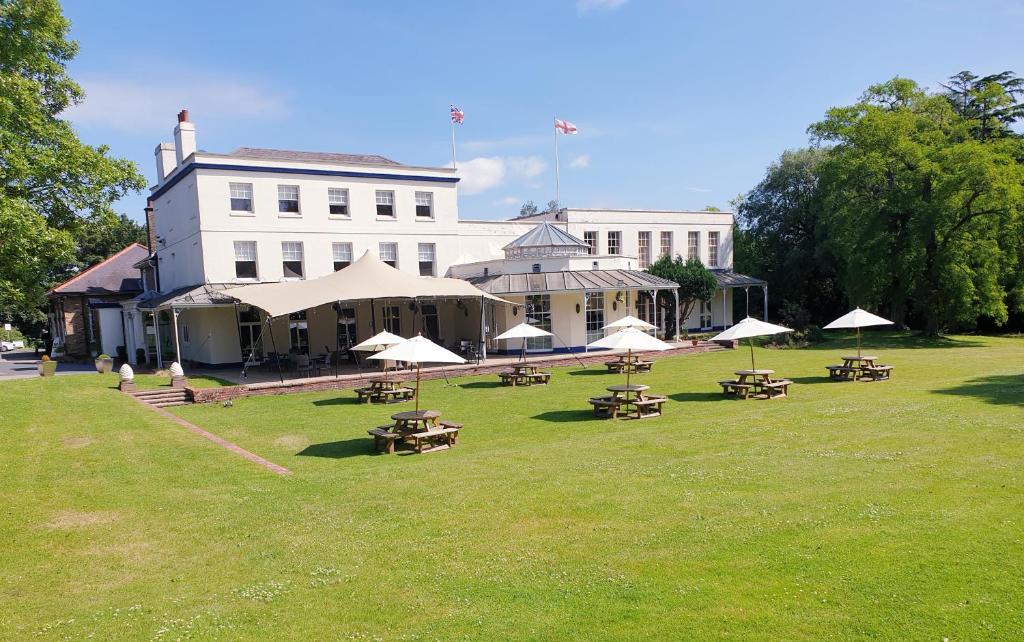 a large building with tables and umbrellas in a park at Stifford Hall Hotel Thurrock in Grays Thurrock