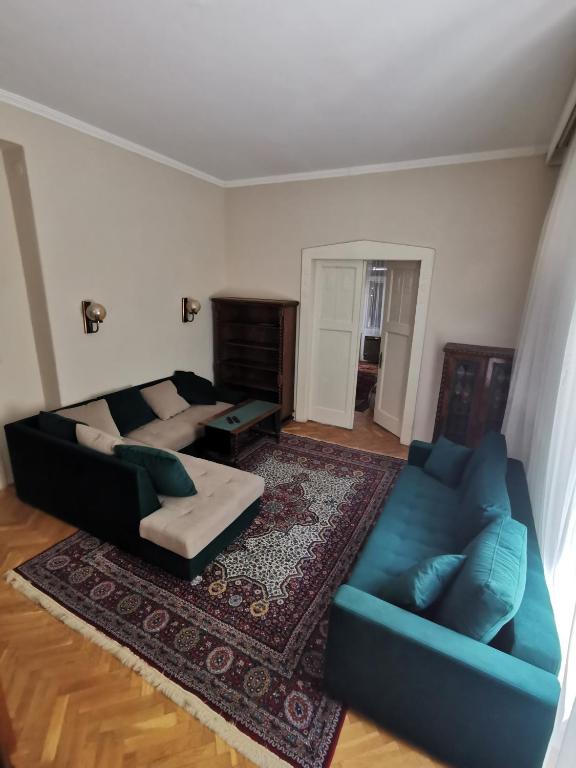 a living room with two blue couches and a rug at Antikvilla Apartman in Szeged
