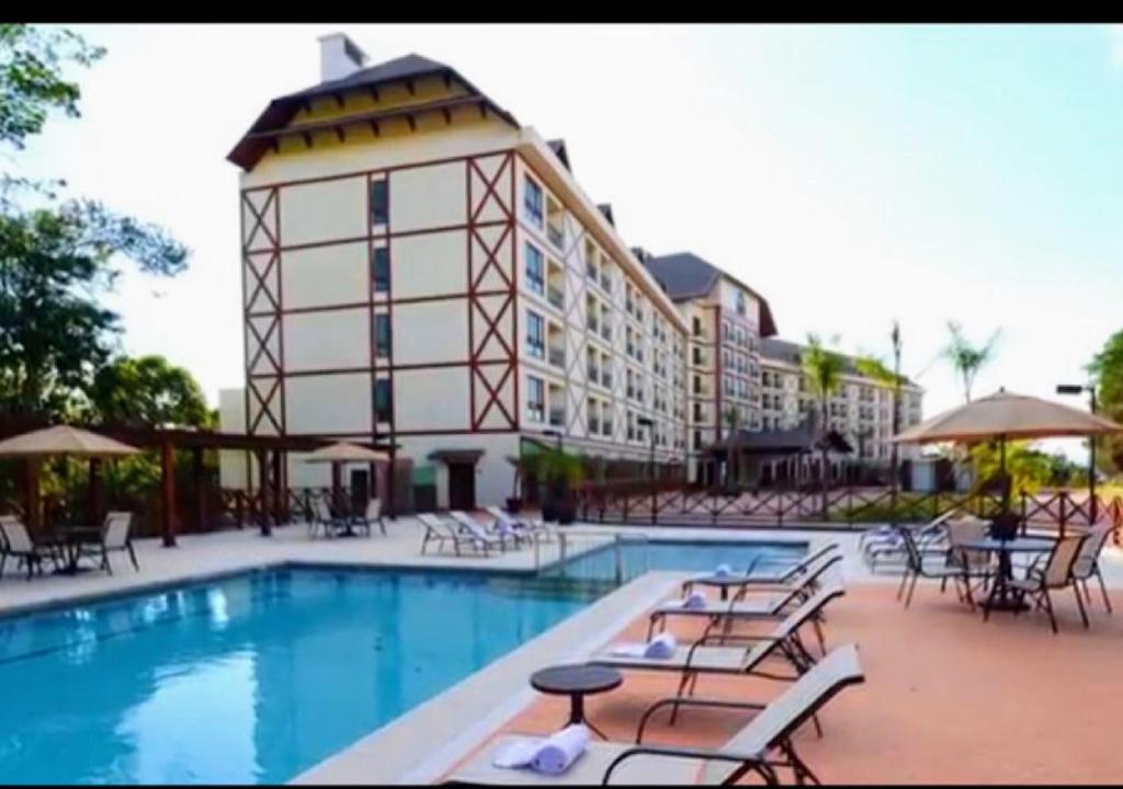un hotel con piscina con sillas y un edificio en Condomínio Vista Azul Residencial Meeting Center en Domingos Martins