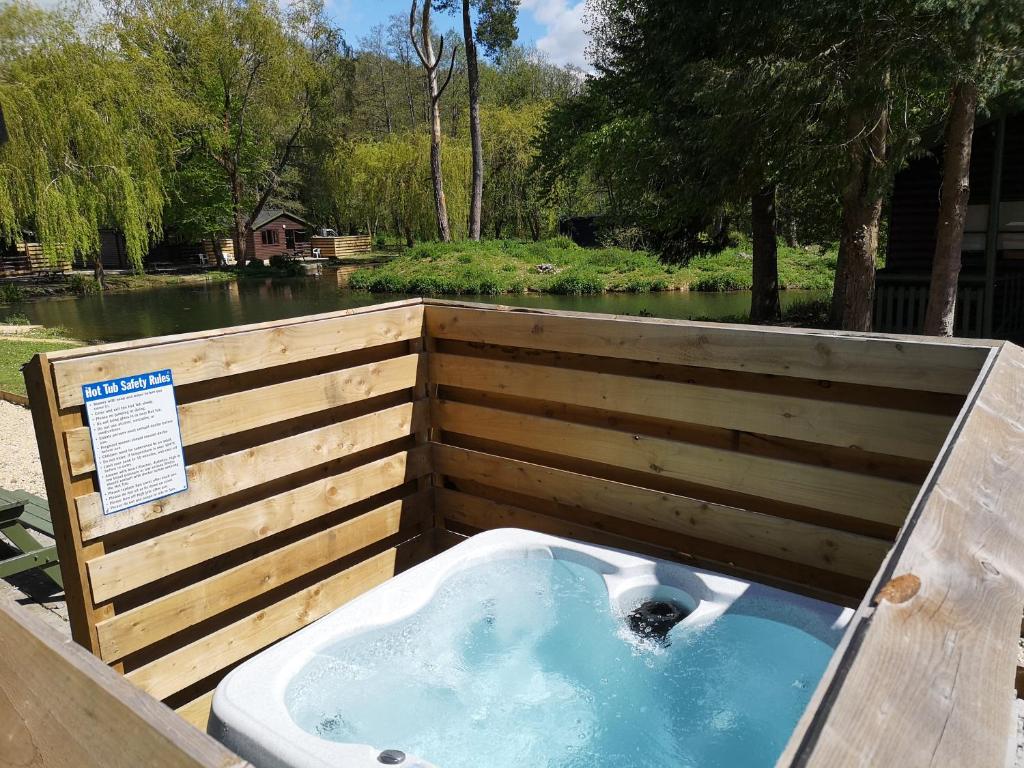 a jacuzzi tub in a fence next to a river at Magpie 4 Hot Tub Huntersmoon-Warminster-Bath-Salisbury in Warminster