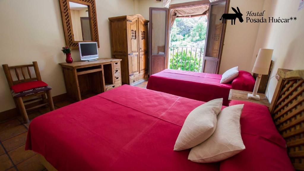 a bedroom with two beds with pink sheets and a television at Hostal Posada Huecar in Cuenca