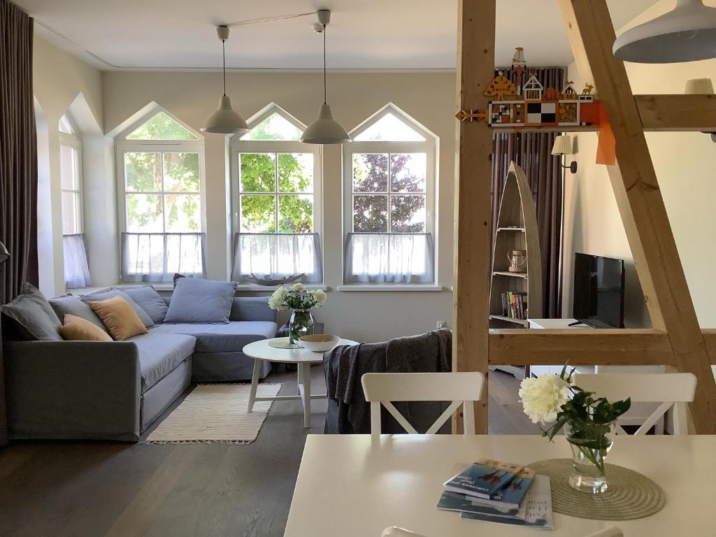 a living room with a blue couch and some windows at Vila MAY in Juodkrantė