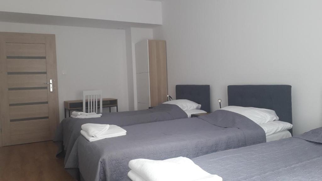 a bedroom with three beds with white towels on them at Apartamenty Irena Stare Miasto Św. Ducha in Elblag