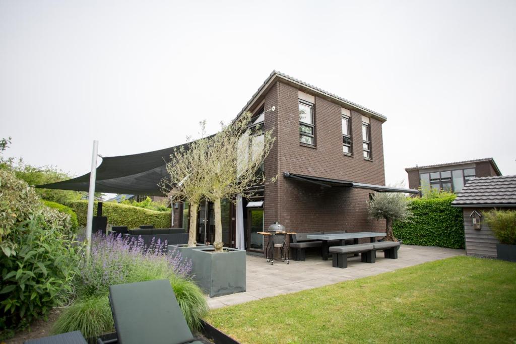 um jardim com uma casa de tijolos e um pátio em Vakantiehuis Olivia em Schoorl