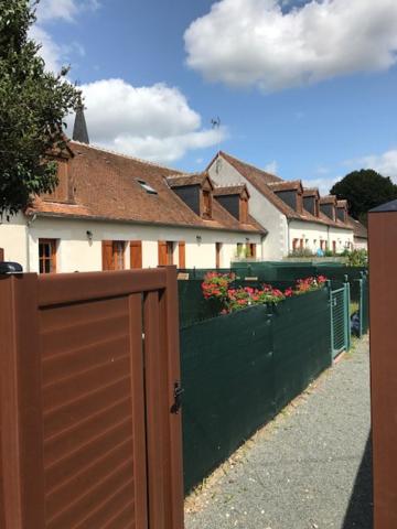 einen Zaun mit brauner Tür vor einem Haus in der Unterkunft Les Terrasses Des Rossignols in Chémery