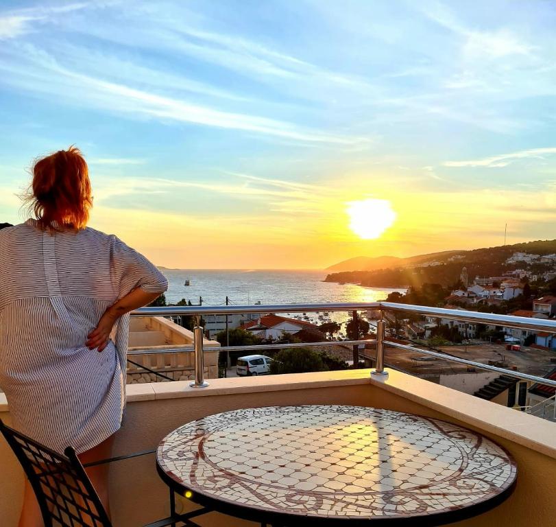 una mujer de pie en un balcón viendo la puesta de sol en Apartments and Rooms Marija, en Hvar