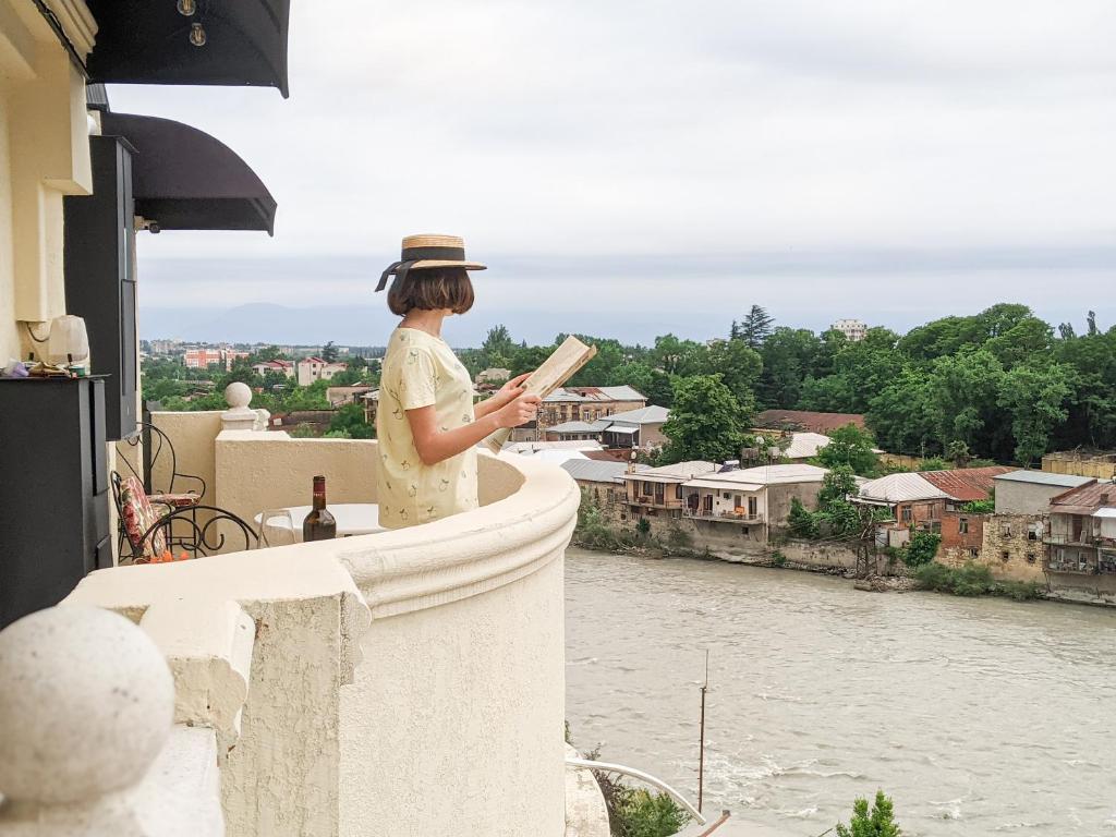 a woman standing on a ledge looking out over a river at Boutique Apartment - Signature in Kutaisi