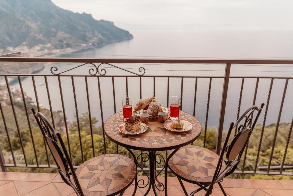 uma mesa com comida e bebidas numa varanda em Lo Sguardo sull' Infinito em Ravello