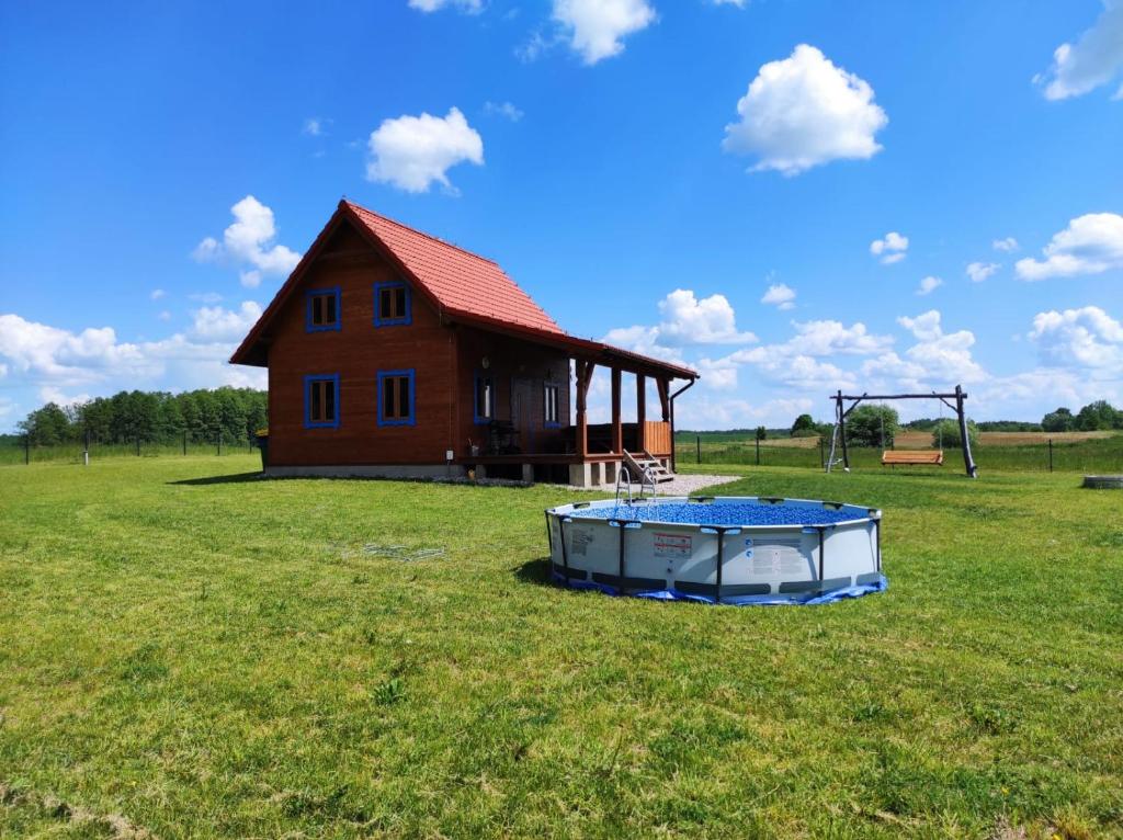 a house with a pool in a field next to a building at Mazurska Chatka Puchatka in Piecki