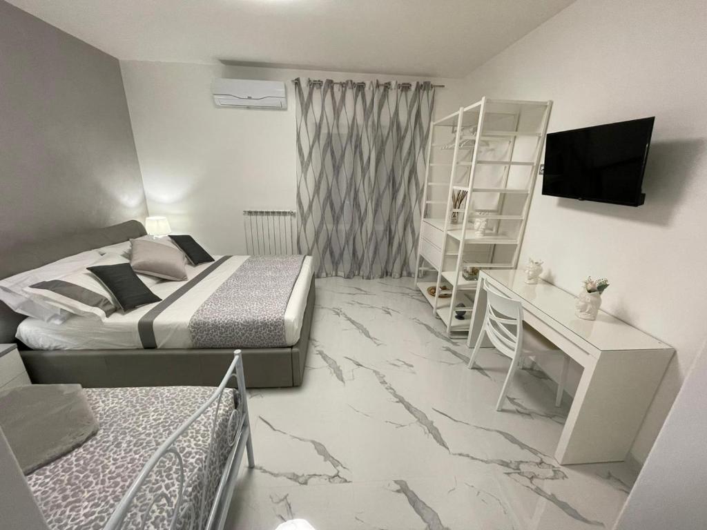 1 dormitorio con 2 camas, escritorio y TV en B&B IL PICCOLO PRINCIPE, en Mercato San Severino