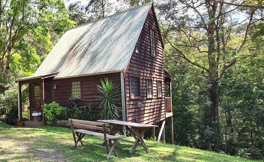 a wooden cabin with a bench in front of it at Hidden Haven Barrington Tops in Cobark