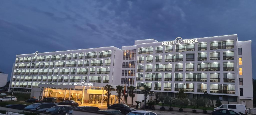 a hotel building with cars parked in a parking lot at Hotel Terra in Neptun