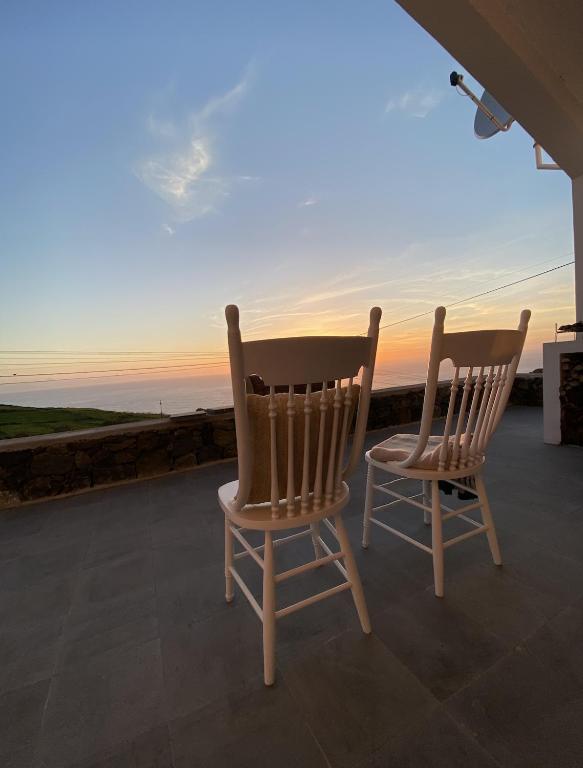 two chairs sitting on a porch looking out at the ocean at Casa da Ribeira do Além in Angra do Heroísmo