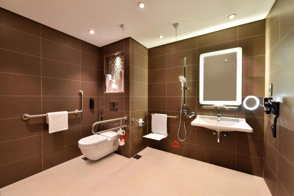 a bathroom with a toilet and a sink and a mirror at Bahrain Airport Hotel Airside Hotel for Transiting and Departing Passengers only in Muharraq