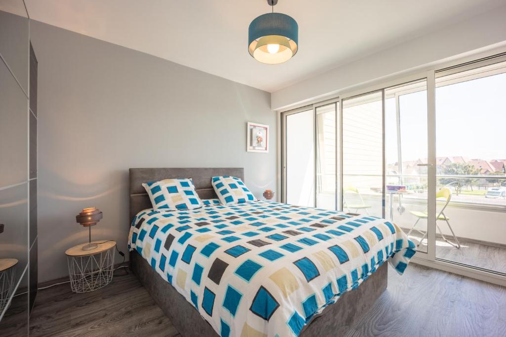 a bedroom with a bed and a large window at Les Vagues in Courseulles-sur-Mer