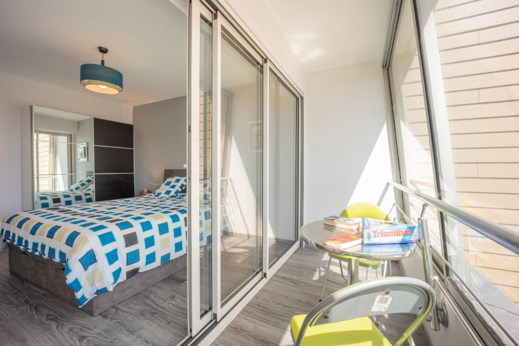 a bedroom with a bed and a balcony at Les Vagues in Courseulles-sur-Mer