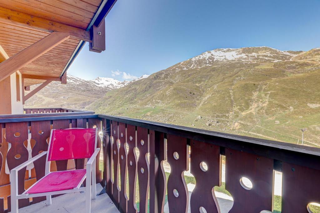 una silla roja sentada en un balcón con una montaña en Les Valmonts 403, en Les Menuires