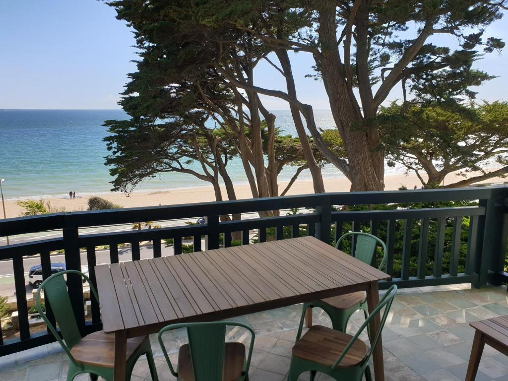 una mesa de madera y sillas en un balcón con vistas a la playa en Les Cigales, en La Baule