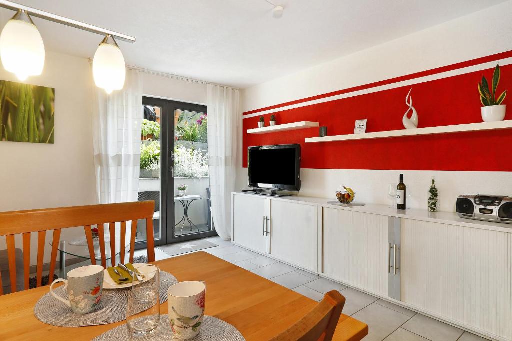 a kitchen with red walls and a dining room with a table at Ferienwohnung Sauermann in Markdorf