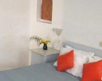 a bedroom with a bed with orange and white pillows at Agistri Club Hotel in Skliri