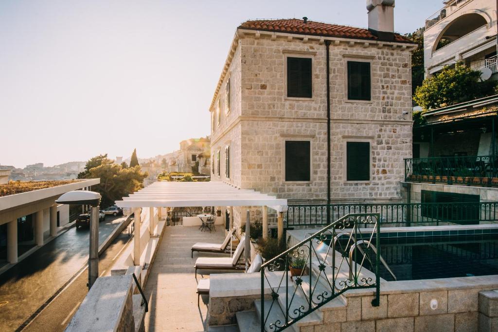 un edificio con piscina y sombrilla blanca en Villa Allure of Dubrovnik en Dubrovnik