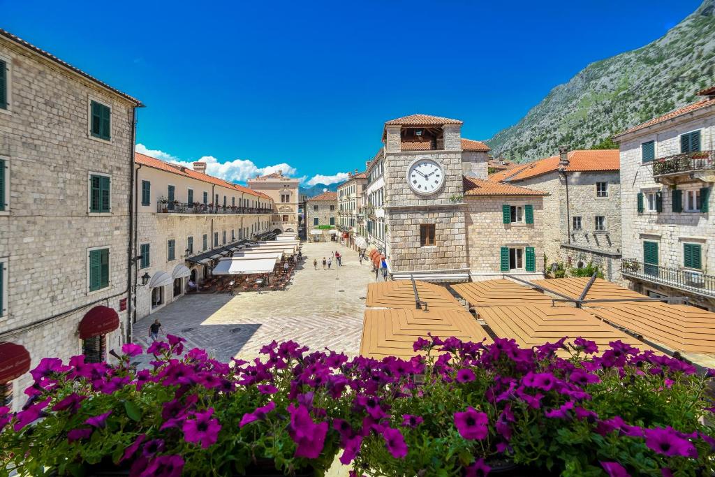 a town with a clock tower and purple flowers at Apartments Hun in Kotor