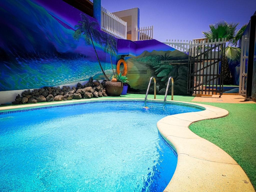 a swimming pool in a backyard with a mural at Surf Riders Fuerteventura in Corralejo