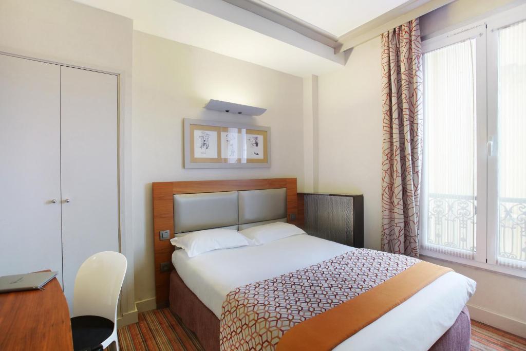 1 dormitorio con cama, escritorio y ventana en Hotel Berne Opera, en París