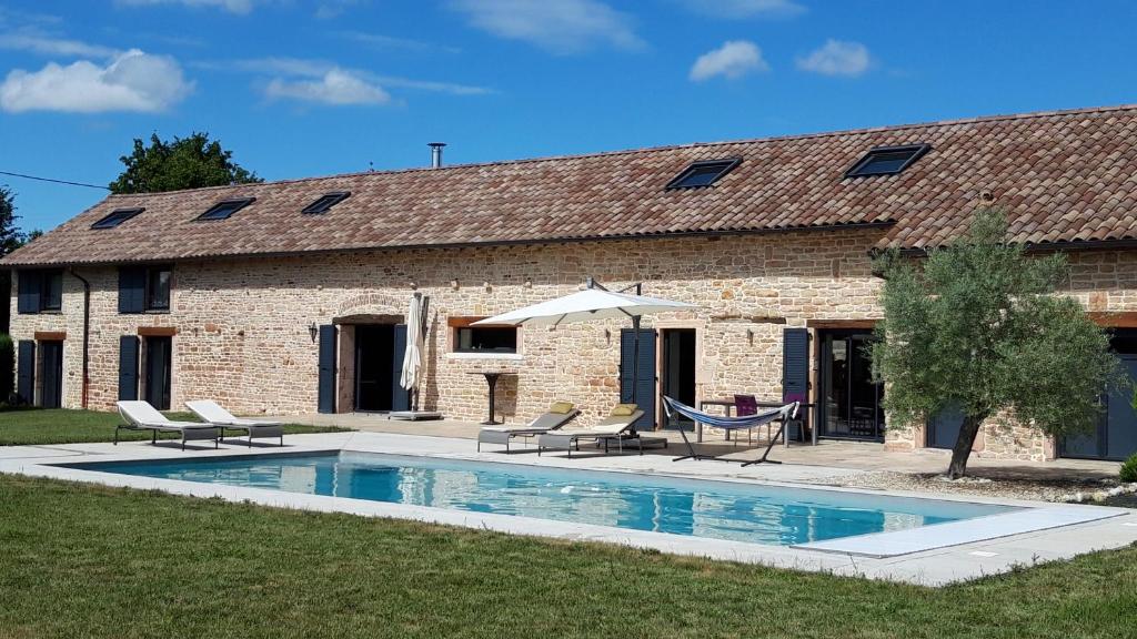 uma piscina em frente a um edifício com cadeiras e um guarda-sol em La Lézardine em Ratenelle