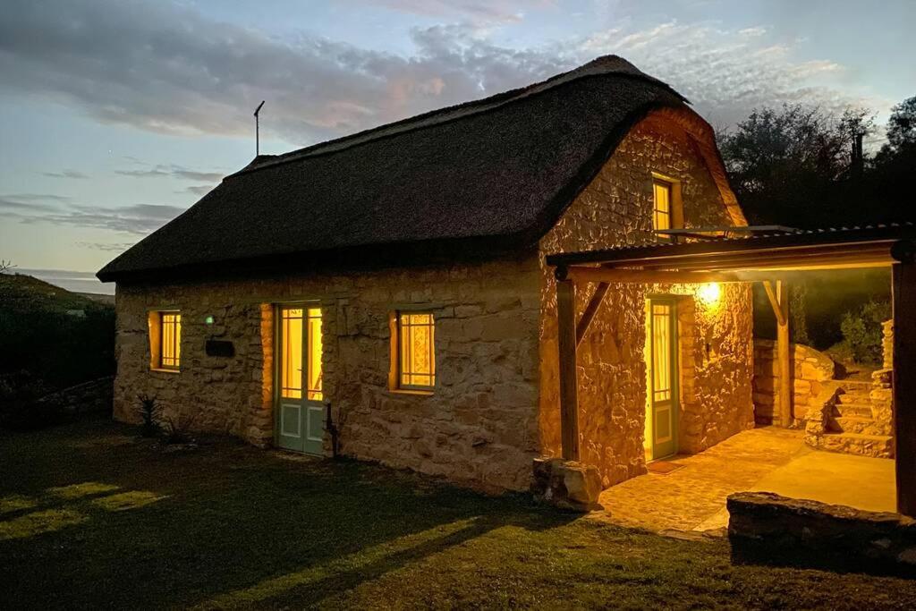 une petite maison en pierre avec des lumières sur son côté dans l'établissement Paddahoek Cottage, à Vermaaklikheid
