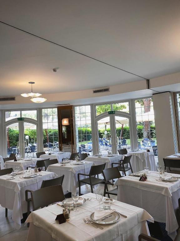 a restaurant with white tables and chairs and windows at Vittoria Parc Hotel in Bari