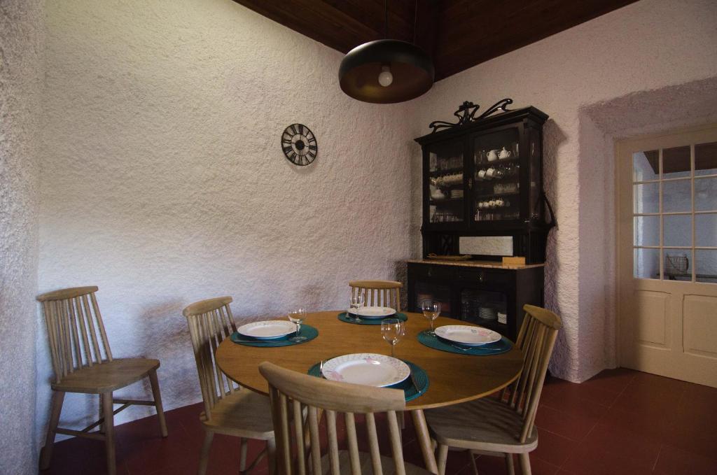 a dining room table with chairs and a clock on the wall at Quinta do Mirante 1785 in Ponta Delgada