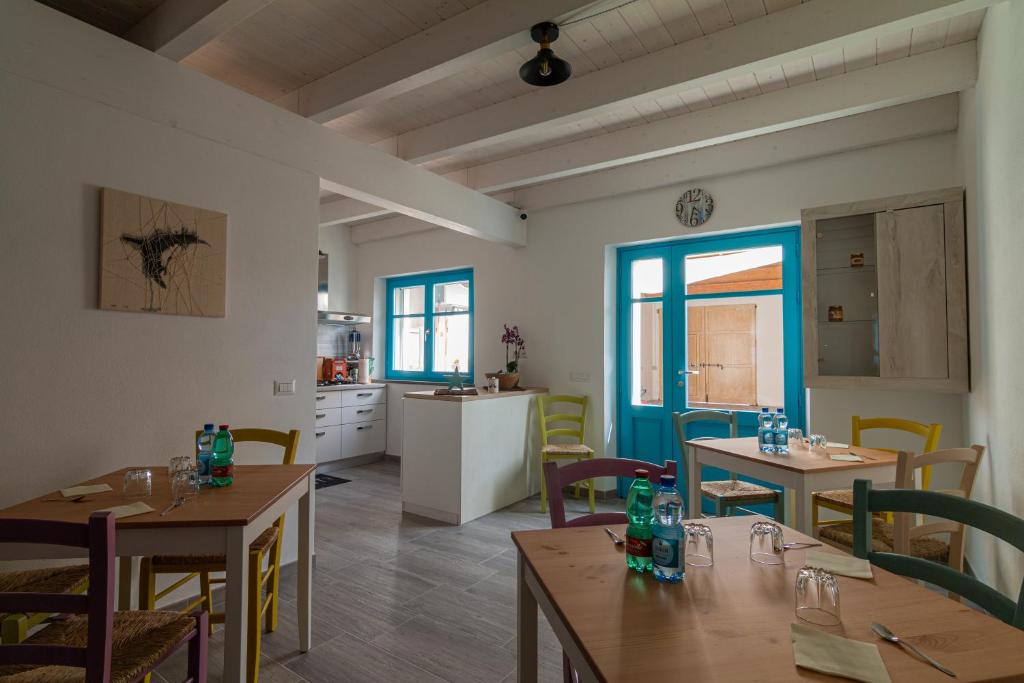 um restaurante com mesas e cadeiras e uma cozinha em La Vecchia Dimora em Marrùbiu