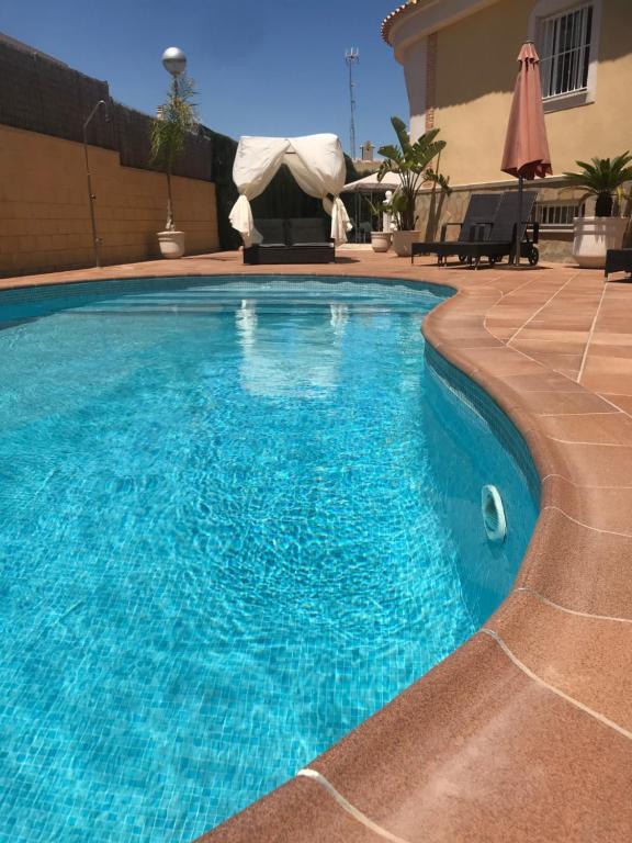 uma piscina com água azul em frente a uma casa em Vickys Villa em Puerto Marino