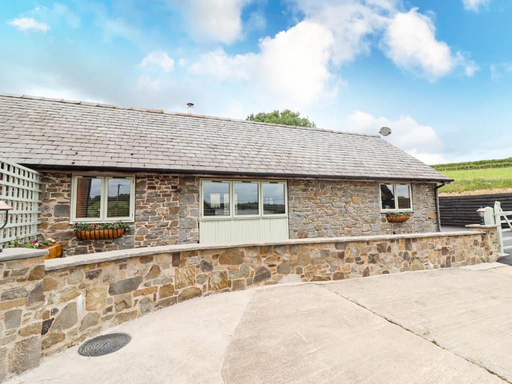 a stone house with a stone wall at Beudy Bach Y Garth in Newtown