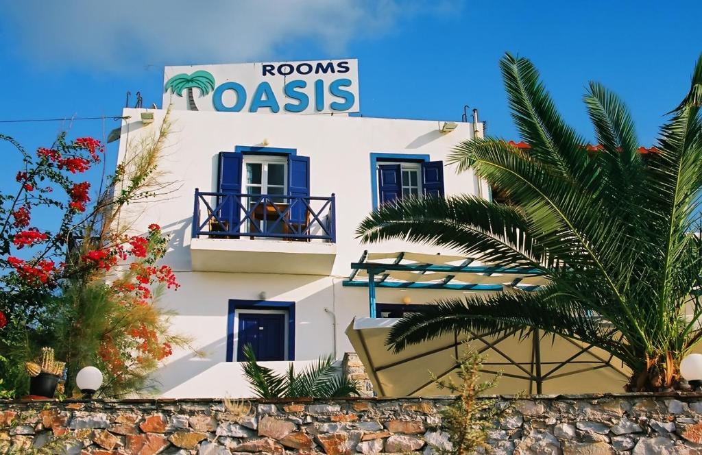 a white building with a sign that reads rooms roses at Oasis Azolimnos in Azolimnos Syros