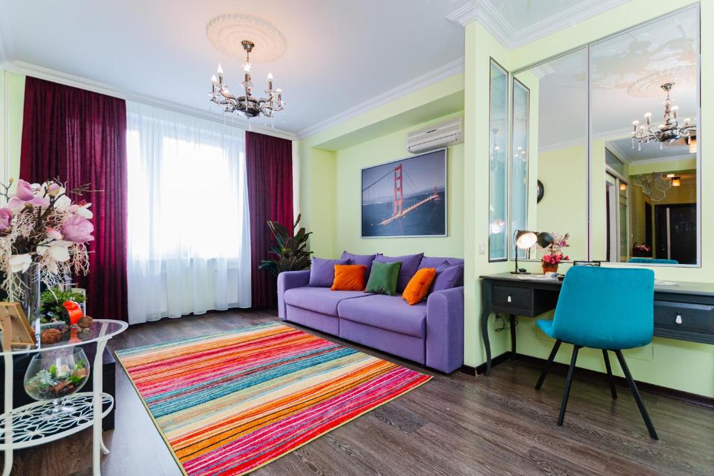 モスクワにあるLakshmi Apartment Novy Arbat 3-bedroomの紫色のソファとデスク付きのリビングルーム