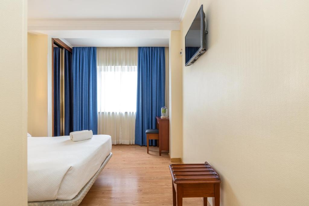 a hotel room with a bed and a window at Hotel Residencial Colibri in Costa da Caparica