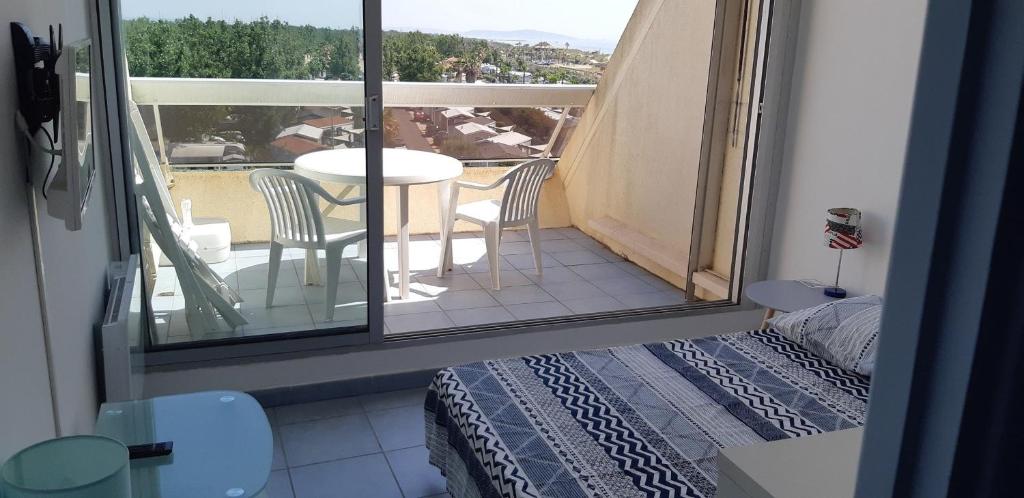 une chambre avec un balcon avec une table et des chaises dans l'établissement Naturiste Cap d'Agde Héliopolis L 24, au Cap d'Agde