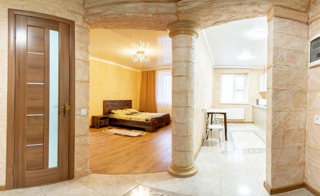 Cette chambre dispose d'un pilier avec un lit et une table. dans l'établissement Новые апартаменты на Зарванской., à Kamianets-Podilsky