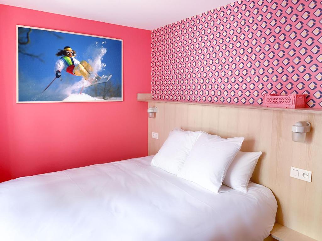 um quarto com uma cama branca e uma fotografia de um esquiador em Cosmiques Hotel - Centre Chamonix em Chamonix-Mont-Blanc